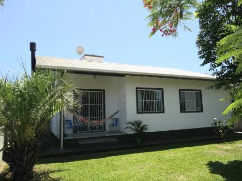 加罗帕巴Casa de praia na Gamboa - Garopaba SC的绿色庭院的白色房子