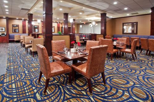 独立市Ramada by Wyndham Cleveland Independence的一间铺有地毯并配有桌椅的餐厅