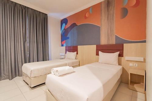 万隆RedDoorz At Hotel Arimbi Dewi Sartika Baru的酒店客房设有两张床,墙上挂有绘画作品