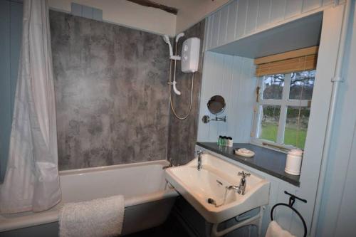 布莱尔高里Blairbeg Cottage的带浴缸、水槽和浴缸的浴室