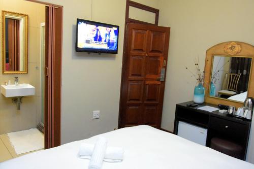 约翰内斯堡霍顿宾馆的一间卧室配有一张床、镜子和电视