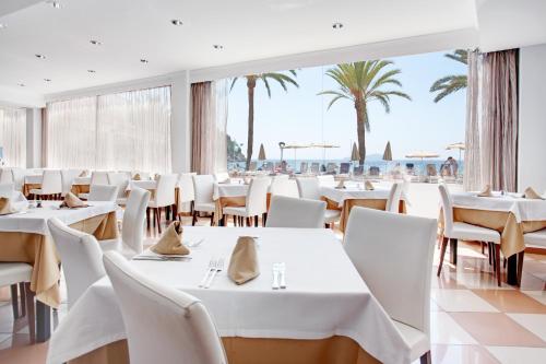 圣胡安包蒂斯塔Grupotel Imperio Playa的餐厅拥有白色的桌椅和棕榈树
