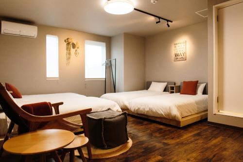 旭川Lampstand STAY Asahikawa的酒店客房带两张床和一张桌子以及椅子。