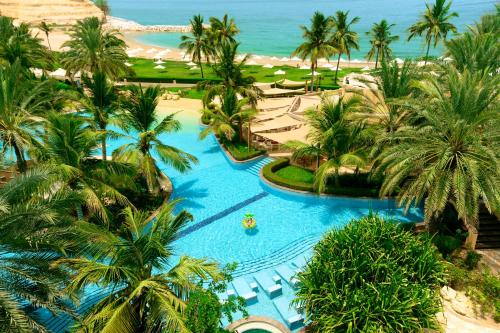 马斯喀特香格里拉巴尔吉萨Spa度假酒店的享有棕榈树度假村游泳池的空中景致