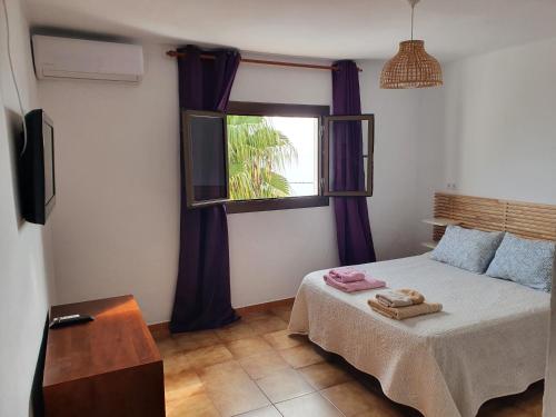 莫哈卡尔Casaflor的一间卧室配有一张带紫色窗帘的床和窗户。