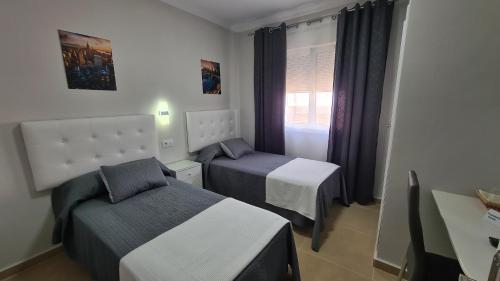 阿尔科斯-德拉弗龙特拉马拉加旅馆的一间小卧室,配有两张床和窗户