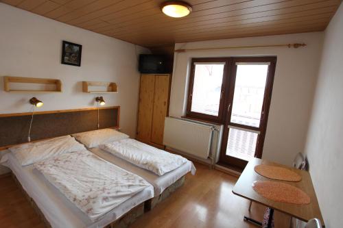 哈沃福卡Penzión Antónia的一间卧室配有一张床、一张桌子和一个窗户。