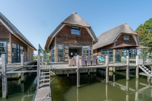 De HeenNautic Rentals - Watervilla's Zuiderhoeve的水面上的房子,有码头