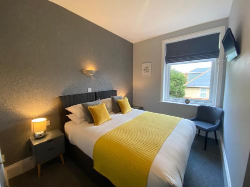伯恩茅斯切尔西酒店的一间卧室配有一张带黄色毯子和窗户的床