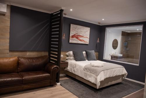 约翰内斯堡The Royal Bryanston的一间卧室配有一张床、一张沙发和一面镜子