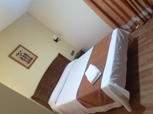 莫塞永芭堤雅酒店的卧室配有白色的床和木制床头板