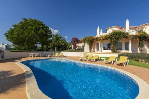 费拉古多Villa with beautiful see views & spacious garden的一个带椅子的游泳池以及一座房子