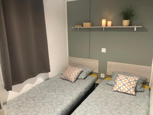 雷日卡普费雷Mobil home au calme au Cap-Ferret - Camping en première ligne du bassin的客房设有两张带枕头和架子的床。
