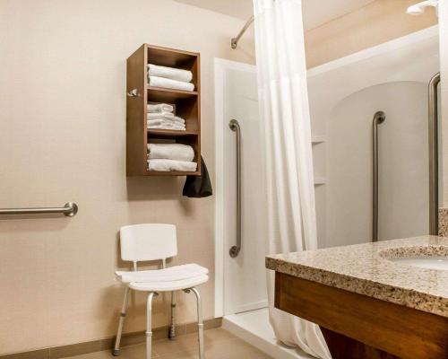 斯特布里奇Comfort Inn & Suites Sturbridge-Brimfield的浴室设有水槽和淋浴旁的椅子