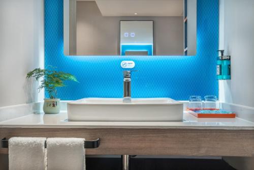 长沙长沙高铁南站智选假日酒店的浴室设有白色水槽和蓝色的墙壁