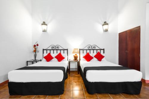 瓦哈卡市Capital O El Nito Posada的宿舍间内的两张床,配有红色枕头