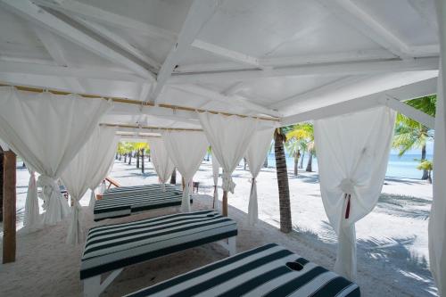 邦劳薄荷海滩俱乐部酒店的海滩上白色天篷下的四把躺椅