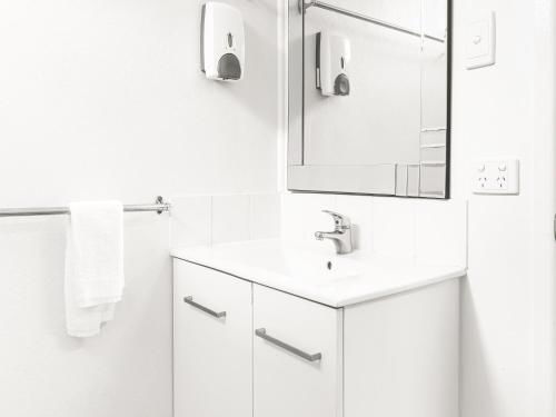麦凯清凉棕榈汽车旅馆的白色的浴室设有水槽和镜子