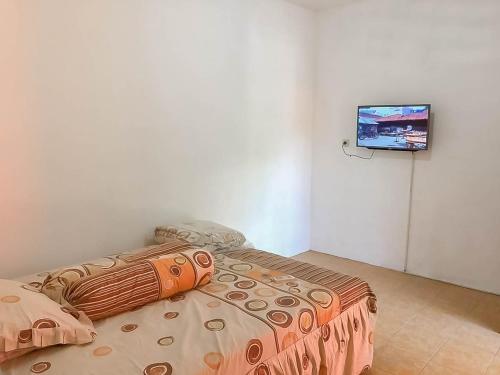 井里汶Rumah Panggung Guest House Syariah Mitra RedDoorz的一间卧室配有一张床,墙上配有电视