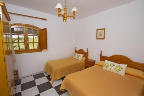 埃尔博斯克El Almendral的一间卧室设有两张床,铺有一个 ⁇ 板地板