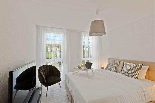 埃帕林格斯Olympia Homes beautifully furnished flats的一间卧室配有一张床、两把椅子和电视