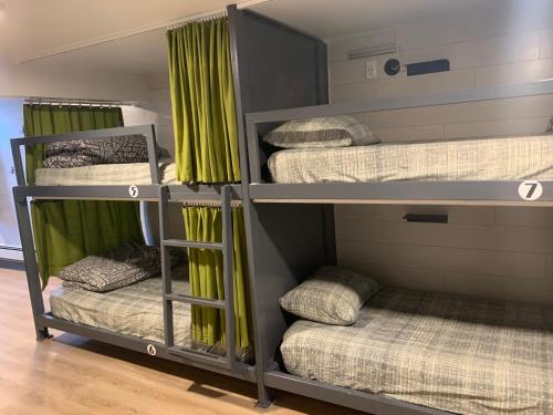 贾斯珀贾斯珀市中心旅舍的带绿色窗帘的客房内的四张双层床