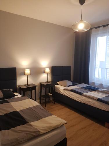 卡托维兹Sun Apartment Katowice Chorzów的一间卧室设有两张床和两张带台灯的桌子。