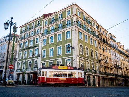 里斯本Figueira by The Beautique Hotels & Spa的大楼前的红色和白色电车