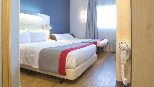 阿尔考空Holiday Inn Express Madrid-Alcorcón, an IHG Hotel的配有窗户的酒店客房内的两张床