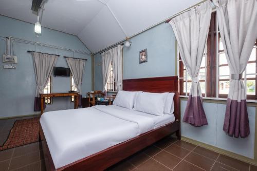 关丹OYO 89873 Nurbayu Chalet的一间卧室配有一张带白色床单和窗户的床。