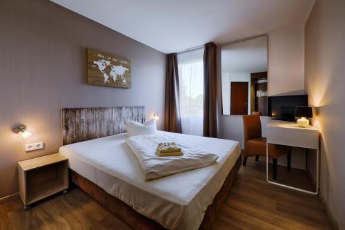 施科伊迪茨REGIOHOTEL Leipzig West的酒店客房配有一张床、一张书桌和一张书桌。