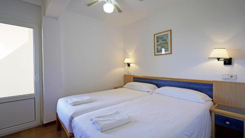 埃斯普霍斯Apartamentos Portu Saler的一间卧室设有两张带白色床单的床和窗户。