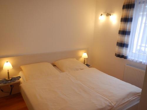 黑尔戈兰岛艾尔葛洛斯提贝公寓的卧室配有白色的床和2个枕头