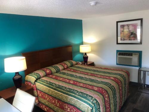 乔治敦Econo Lodge的一间卧室配有一张带彩色毯子和两盏灯的床。