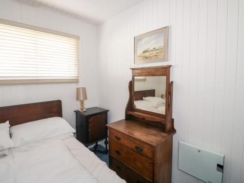 韦德布里奇Driftwood的一间卧室配有一张床,梳妆台上配有镜子