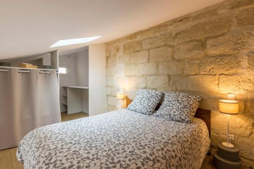 蒙彼利埃La Parenthèse Roucher Montpellier - Duplex Climatisé T2 Cœur écusson的一间卧室设有一张大床和石墙