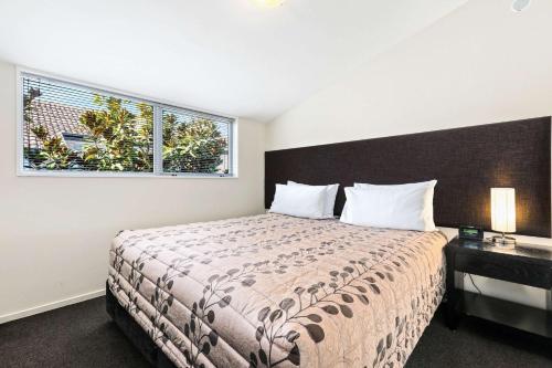 基督城Quality Suites Amore的一间卧室设有一张大床和一个窗户。