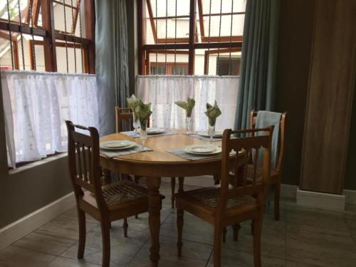 乔治Rozenhof Guest Cottages的餐桌,配有四把椅子和一张木桌,桌子上摆放着盘子和花瓶