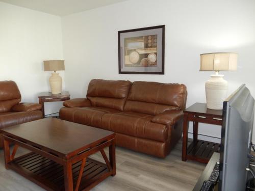 好莱坞Shell Motel Hollywood的客厅配有棕色皮沙发和桌子
