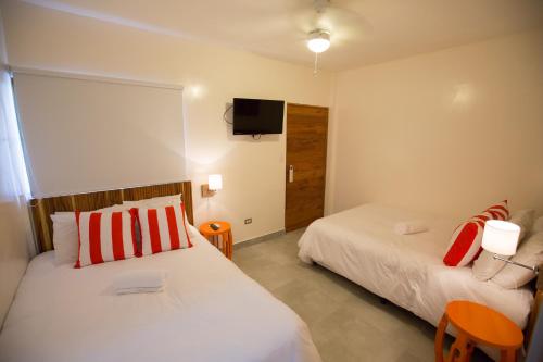 南圣胡安El Caite San Juan del Sur的一间卧室设有两张床,墙上配有电视。