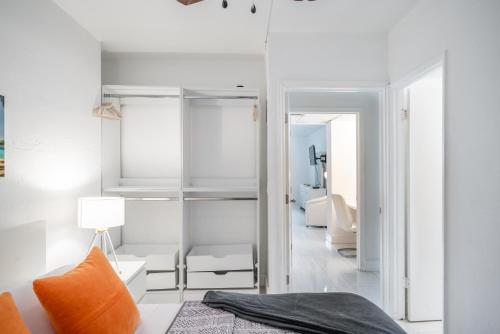 迈阿密海滩Sunny Isles Ocean Reserve Superb Condo Apartments的卧室设有白色墙壁和1张带橙色枕头的床