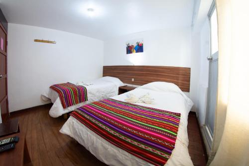 普诺Inka's Rest Hostel的一间卧室配有两张床和彩色毯子