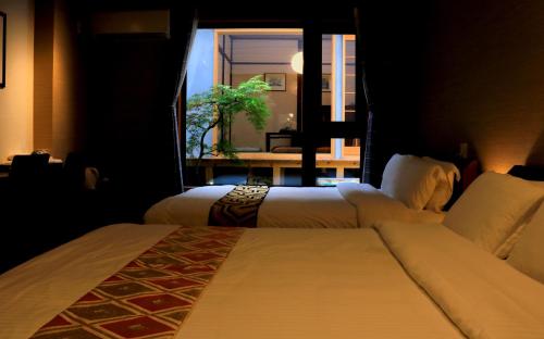 京都Hotel Traveling Bridge Nijojo的配有窗户的酒店客房内的两张床