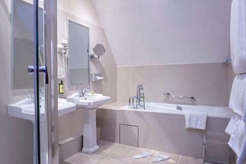 蒙特勒伊蒙特里城堡酒店的白色的浴室设有两个盥洗盆、一个浴缸和镜子