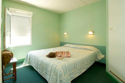 莱斯坎里尔-莱斯坎机场法斯特酒店的一间绿色卧室,配有一张带帽子的床