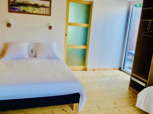 拉尼翁La Miellerie的卧室配有白色的床和玻璃门