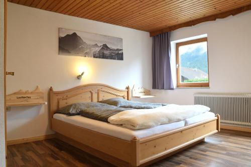 HäselgehrPension Lichtspitze的一间卧室配有一张木床和窗户
