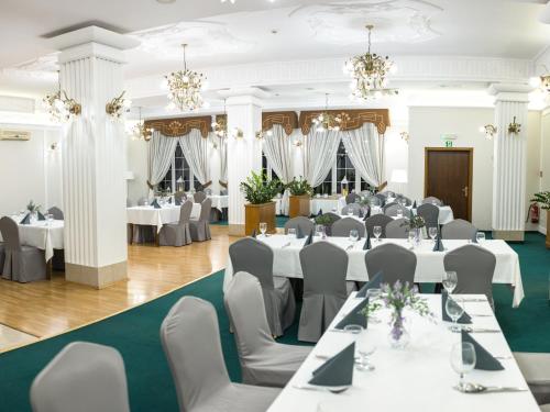热舒夫Hotel Villa Riviera的宴会厅配有白色的桌椅和吊灯
