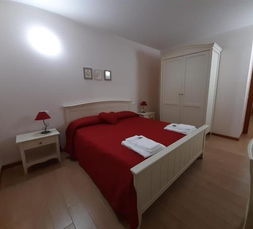PolcenigoAlbergo Diffuso Polcenigo C.Barnard的一间卧室配有一张红色大床和两张桌子