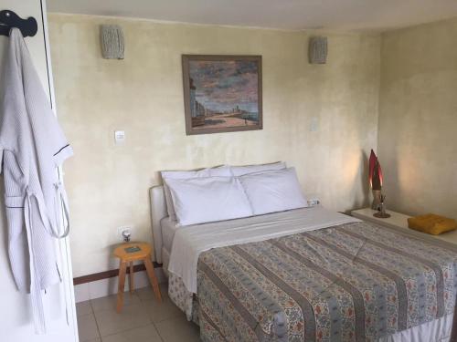 布希奥斯Suite Independente Por do Sol Ferradura的卧室配有一张床,墙上挂有绘画作品
